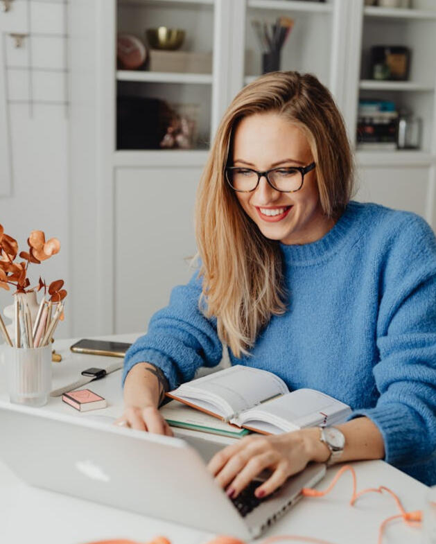 femme blonde souriante devant son ordinateur en train de travailler